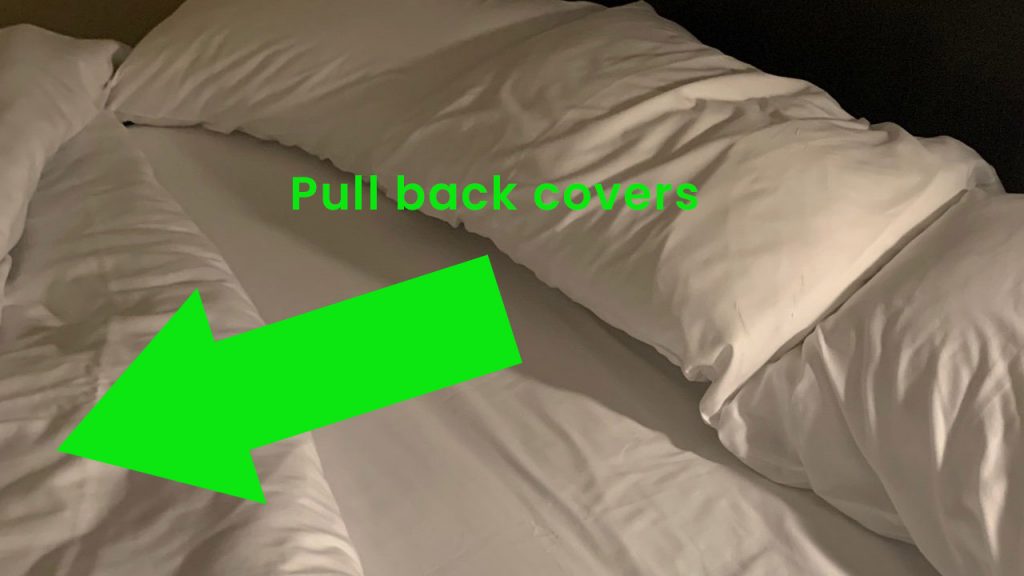 Bed with its covers pulled back.